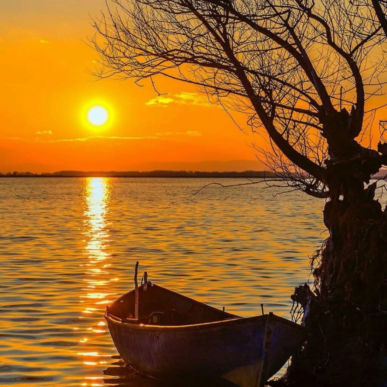 Sunset over the water with a fishing boat